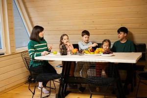 Mother with four children eat fruits in wooden country house on weekend. photo