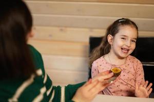 madre con hija comer frutas, ella dio un pasión fruta. foto