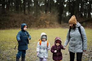 Mother with kids holding willow twigs while traveling in forest. photo