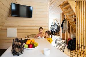 Two sisters eat strawberries in wooden country house on weekend. photo