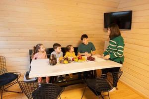 Mother with four children eat fruits in wooden country house on weekend. photo