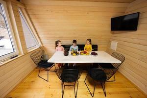 Three children eat fruits in wooden country house on weekend. photo