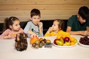 cuatro niños comer frutas en de madera país casa en fin de semana. foto