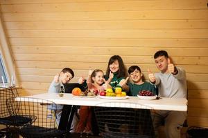 familia con Tres niños comer frutas en de madera país casa en fin de semana y muestra pulgar arriba. foto