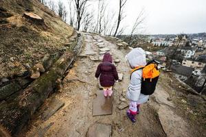 dos muchachas hermanas caminar arriba el mojado camino a un antiguo fortaleza en lluvia. foto