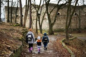 Back of mother and kids walk path to an ancient medieval fortress in rain. Terebovlia castle, Ukraine. photo