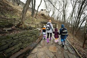 Back of mother and children walk up the wet path to an ancient medieval castle fortress in rain. photo