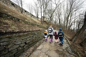 Back of mother and children walk up the wet path to an ancient medieval castle fortress in rain. photo