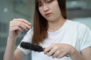 Asian woman have problem with long hair loss attach to comb brush. photo