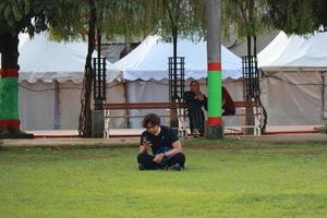 Kudus, December 2022. Photograph of visitors sitting relaxed enjoying the afternoon on the grass of the Kudus city square. photo