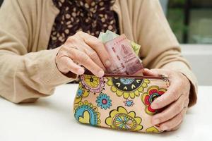 Retired elderly woman counting coins money and worry about monthly expenses and treatment fee payment. photo