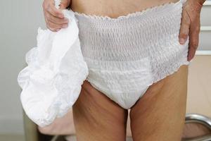 Asian elder senior woman patient wearing adult incontinence diaper pad in hospital. photo