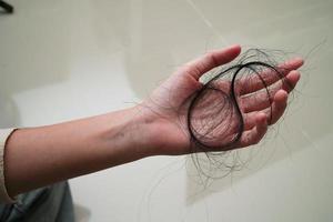 la mujer asiática tiene un problema con la pérdida de cabello largo en su mano. foto