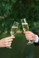 The bride and groom are holding two champagne glasses for the wedding ceremony photo