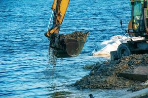 Dnepropetrovsk, Ukraine - 11.26.2021 Excavator works to strengthen the embankment. Hydraulic excavator working on the river bank. photo