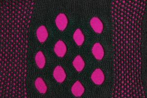Black knitted mesh scarf on a burgundy fabric background. Abstract background. photo