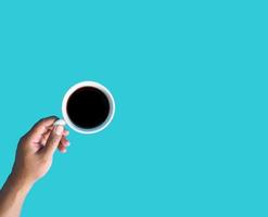 Closeup young adult man hand holding white cup paper of coffee hot drink ready to drink refreshing. aroma awake fresh to work placed on a blue isolated background. Point of view shot. photo