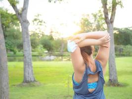 Portrait of a beautiful Asian woman in sportswear, standing with her back, stretching before exercising outdoor in the park in the morning to achieve a healthy lifestyle. healthy  warming up photo
