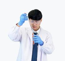 estudiante científico asiático en un laboratorio de mezcla de reactivos en un laboratorio de investigación científica con tubos de ensayo de varios tamaños y microscopios. sobre la mesa en el fondo blanco de laboratorio de química de laboratorio. foto