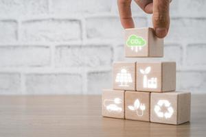 Reduce CO2 emission concept, Person hand holding wooden cube block with Reduce CO2 icon with copy space, Sustainable development and green business based on renewable energy, electric transport. photo