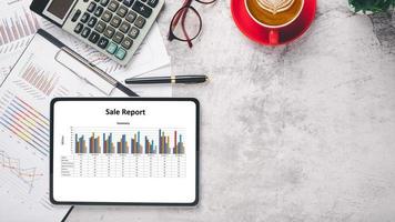 Tablet screen display with charts and reports on office desk workplace. Top view flat lay with copy space. photo