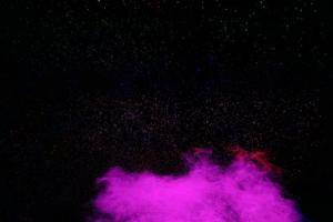 Purple color powder explosion cloud  on black background.Purple dust particles splash. photo