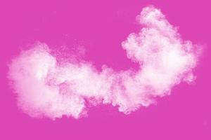 White powder explosion on pink background.White dust particle splashing. photo