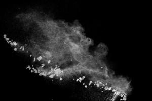 Split debris of  stone exploding with white powder against black background. photo