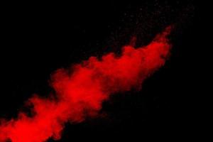 Red powder explosion cloud on black background. Freeze motion of red color dust  particles splashing. photo