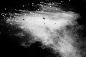 Split debris of  stone exploding with white powder against black background. photo