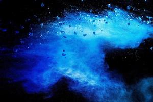 Split debris of  stone exploding with blue powder against black background. photo