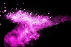 Split debris of stone exploding with pink dust powder against black background. photo