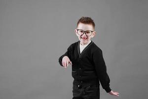 pequeño linda chico con lentes es sonriente y teniendo divertido aislado en gris antecedentes. contento infancia. Copiar espacio foto