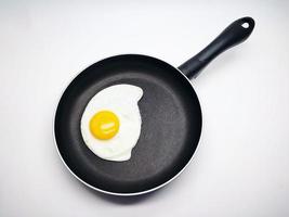 sunny side up eggs on a black pan isolated in white background photo