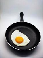 sunny side up eggs on a black pan isolated in white background photo