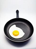 sunny side up eggs on a black pan isolated in white background photo