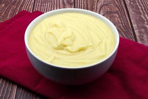 Mashed potatoes in white bowl on rustic table. photo