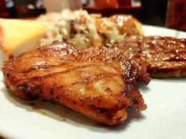 Grilled  chicken steaks, baked potatoes and bread. In a restaurant with warm lighting photo