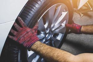 un mecánico es quitando un rueda desde un coche a reemplazar un de repuesto rueda o reparar foto