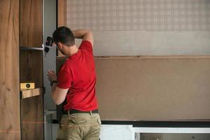 Craftsman, furniture maker and assembler, installs a modern kitchen in the house with tools in hand. Custom furniture concept, home improvement, renovation photo