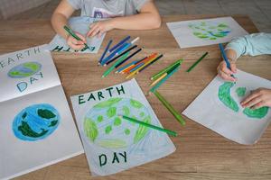 niños dibujar el planeta tierra con lapices y punta de fieltro plumas en álbum hojas para tierra día a su hogar mesa. el concepto de proteger el ambiente, paz en tierra. foto