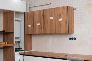 instalación y instalación de un nuevo moderno cocina en el casa. cocina armarios en varios etapas de instalación. foto