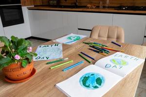 Children's drawings of the planet Earth with a world map with multi-colored pencils on white paper lie on the kitchen table at home. photo