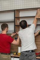 dos artesanos, fabricantes de muebles y ensambladores, están instalando una cocina moderna en una casa, herramientas en sus manos. concepto de muebles por encargo, mejora de las condiciones de vida, reparación foto