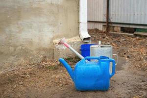 Collection of rainwater in different canisters buckets, watering cans in the yard of his house near the downpipe for further use and watering, space for text photo