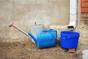 Collection of rainwater in different canisters buckets, watering cans in the yard of his house near the downpipe for further use and watering, space for text photo