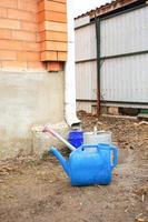 Collection of rainwater in different canisters buckets, watering cans in the yard of his house near the downpipe for further use and watering, space for text photo