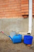 Collection of rainwater in different canisters buckets, watering cans in the yard of his house near the downpipe for further use and watering, space for text photo