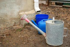 Collection of rainwater in different canisters buckets, watering cans in the yard of his house near the downpipe for further use and watering, space for text photo