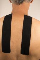 Mature Man with Kinesio Tape on his back for pain management photo